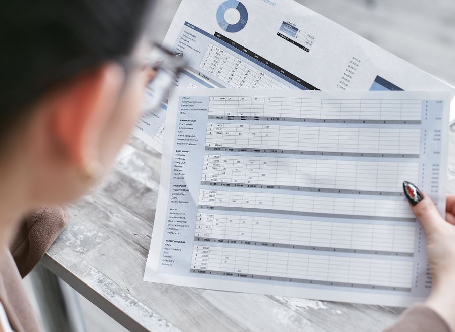 A businesswoman reviewing financial spreadsheets and charts in an office.