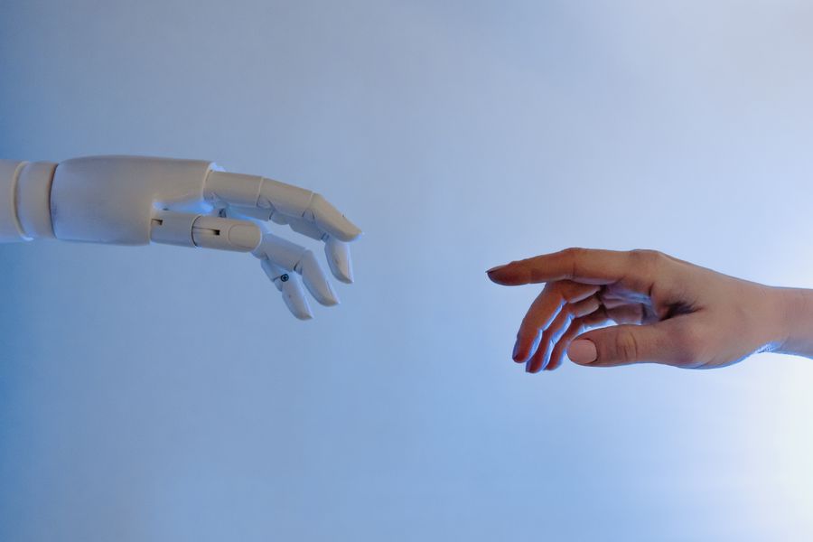 A human hand reaching towards a white robotic hand.