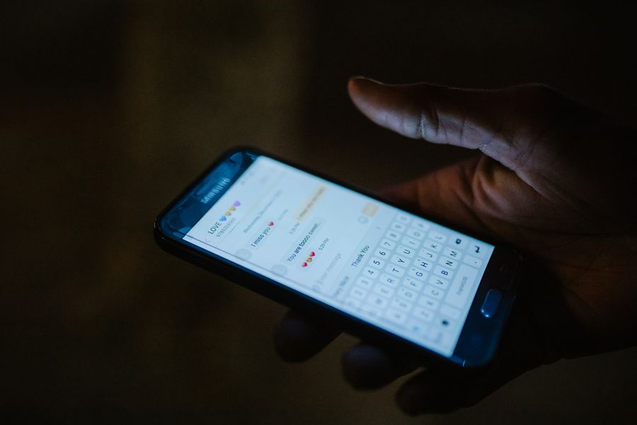 A hand holding a smartphone with a messaging app open.