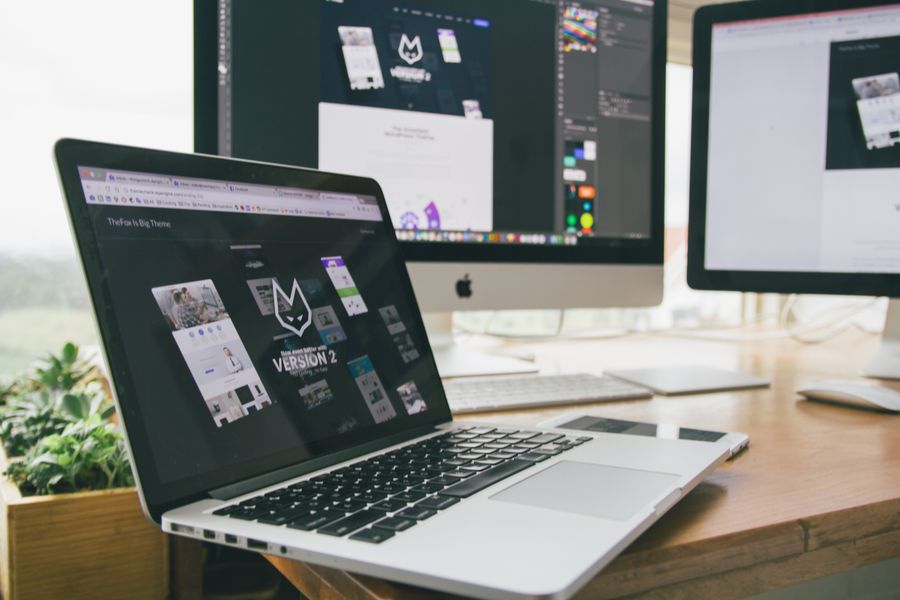 A workspace with a laptop and monitors showing design software.